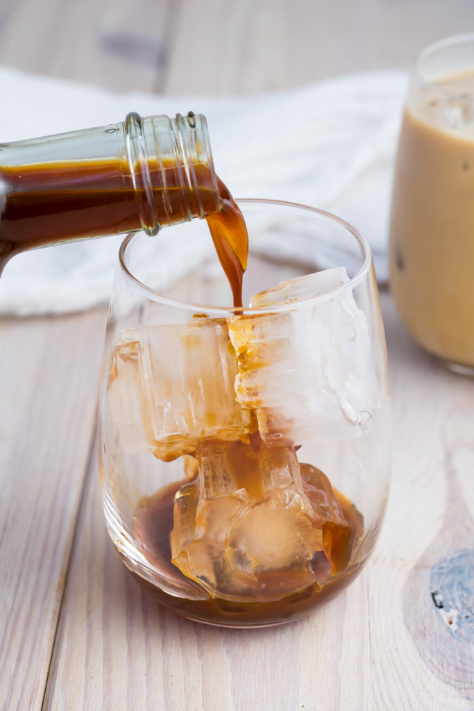 Chai concentrate being poured over ice into a glass.